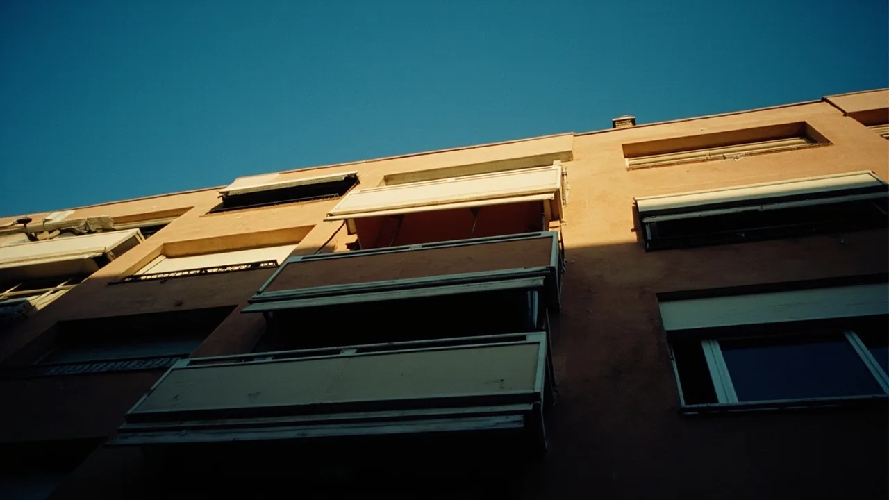 Indivisos inmobiliarios: fachada de un edificio con un balcón iluminado y el resto en sombra