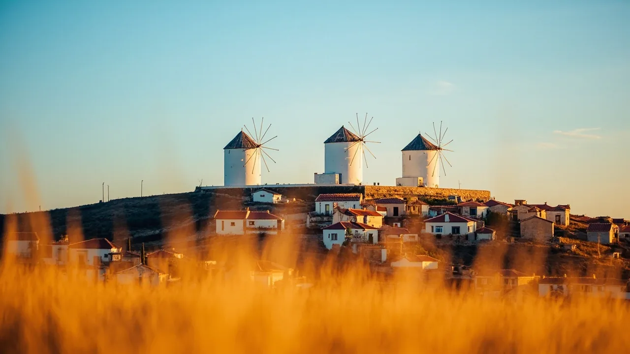 Vender proindiviso en Castilla-La Mancha: molinos blancos sobre un pueblo manchego con campos dorados, donde compramos proindivisos